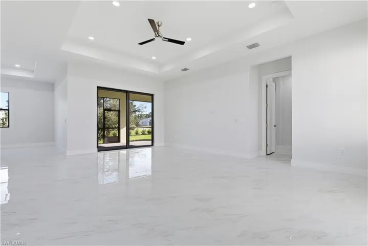 Spare room with a raised ceiling, light marble finish flooring, recessed lighting, and a ceiling fan