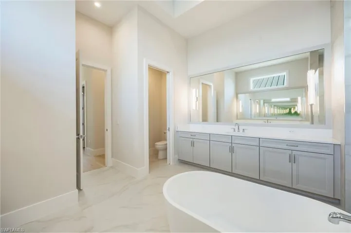 The primary bathroom features dual-entry shower, dual vanities, private water closet, and soaking tub. So much light!