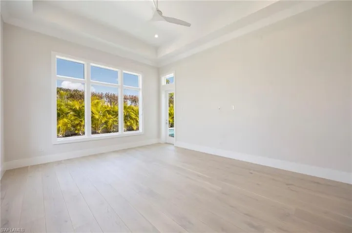 The primary bedroom features large windows overlooking the pool and direct pool deck access via impact glass door.
