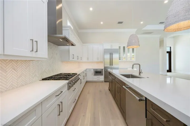 White oak flooring continues through the home into the kitchen. The kitchen featurs white perimater cabinets, wood grain island, Pompeii quartz countertops, marble backsplash, Thermador appliances, pantry, and so much more!