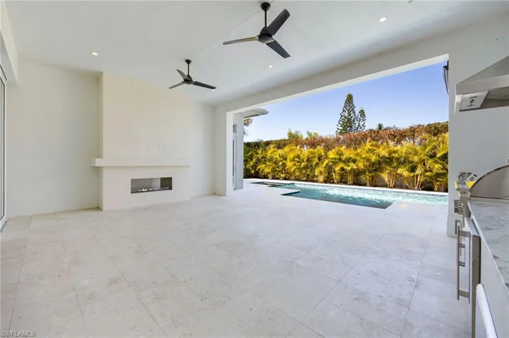 The pool deck features covered and uncovered living space, an outdoor kitchen, outdoor fireplace, and privacy!