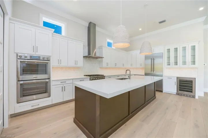 White oak flooring continues through the home into the kitchen. The kitchen featurs white perimater cabinets, wood grain island, Pompeii quartz countertops, marble backsplash, Thermador appliances, pantry, and so much more!