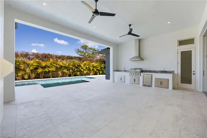The pool deck features covered and uncovered living space, an outdoor kitchen, outdoor fireplace, and privacy!
