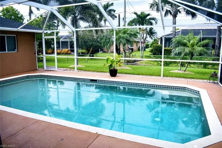 Swimming pool with a yard, glass enclosure, a sunroom, and a patio area