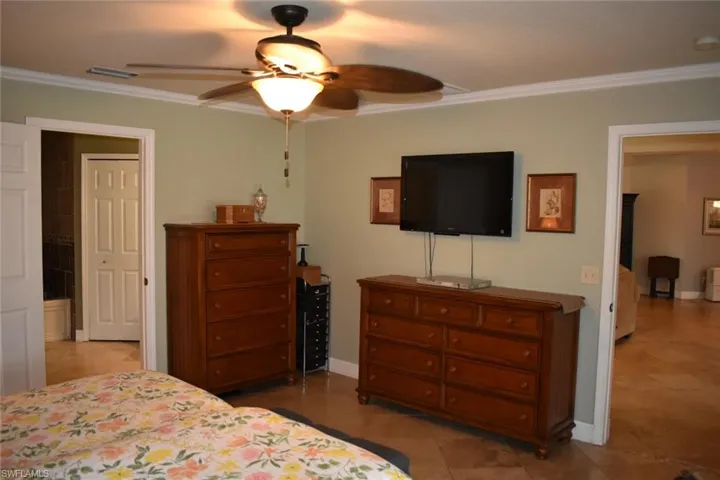 Bedroom with crown molding, a ceiling fan, and light tile patterned floors
