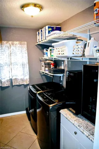Washroom with light tile patterned floors, a textured ceiling, and independent washer and dryer