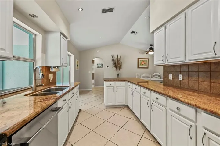 Kitchen featuring tasteful backsplash, vaulted ceiling, a peninsula, arched walkways, and dishwasher