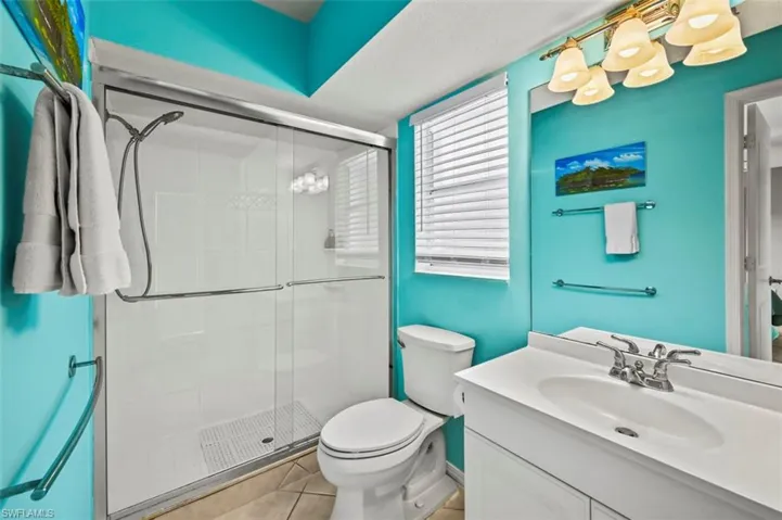 Bathroom with vanity, a stall shower, tile patterned floors, and a chandelier
