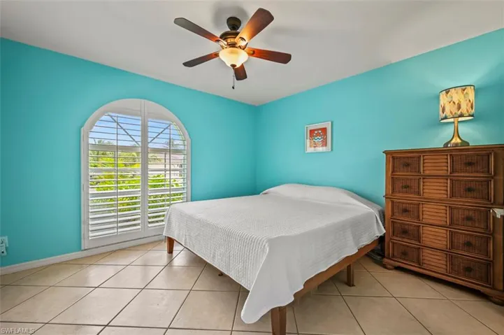 Tiled bedroom featuring ceiling fan
