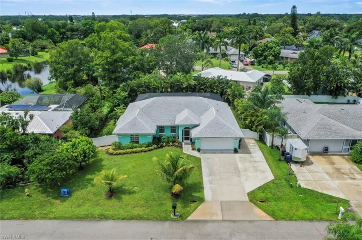 Aerial view of property and surrounding area featuring a tree filled landscape and a large body of water