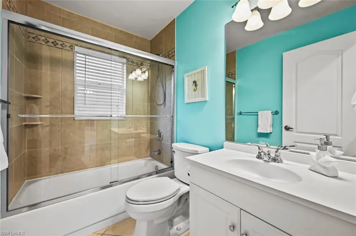 Full bath featuring vanity, bath / shower combo with glass door, and tile patterned flooring
