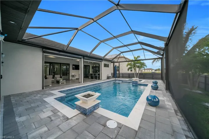 Screened lanai featuring a swimming pool with integrated spa and paver decking