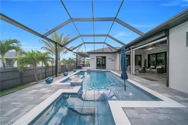 Screened outdoor living area featuring a rectangular pool with integrated spa