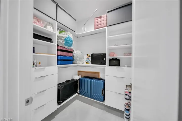 Custom closet system featuring white cabinetry, integrated shelving, and multiple storage drawers with horizontal pulls