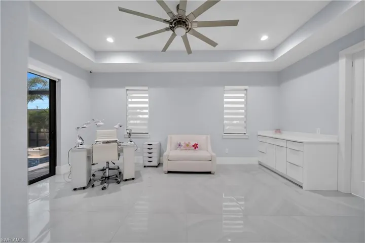 Spacious room with large format tile flooring, tray ceiling, and modern ceiling fan