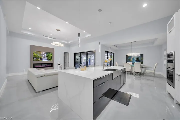 Expansive kitchen island with a waterfall countertop and integrated stainless steel farmhouse sink