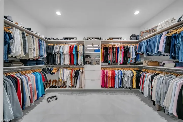 Spacious walk-in closet featuring extensive custom built-in shelving, multiple hanging rods, integrated drawers, and recessed lighting