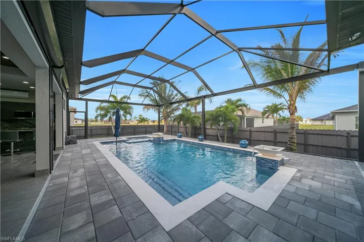 Screened outdoor living area featuring a rectangular pool with integrated spa