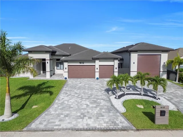 Contemporary-style residence featuring a multi-car paved driveway, a tile roof, stucco exterior, and dual garage doors
