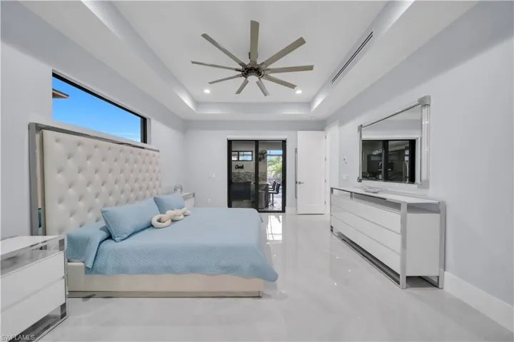 Spacious room featuring light-toned tile flooring, a tray ceiling with recessed lighting, and a modern ceiling fan