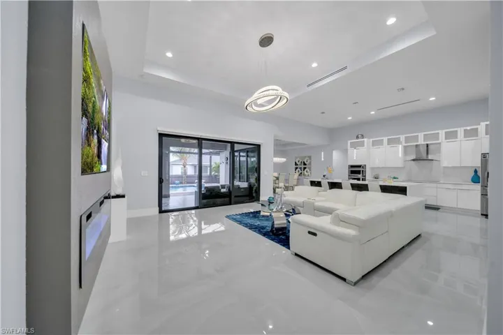 Open-concept living space featuring high ceilings with recessed lighting, large format tile flooring, and a contemporary linear chandelier