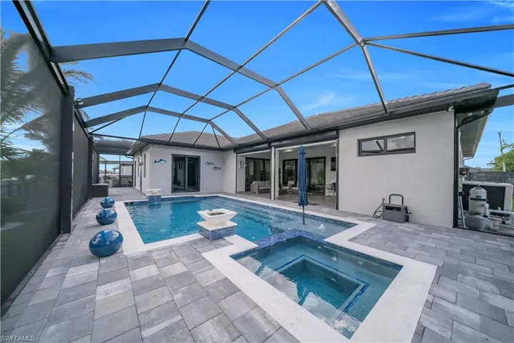 Screened lanai featuring a swimming pool, integrated spa, and paver decking