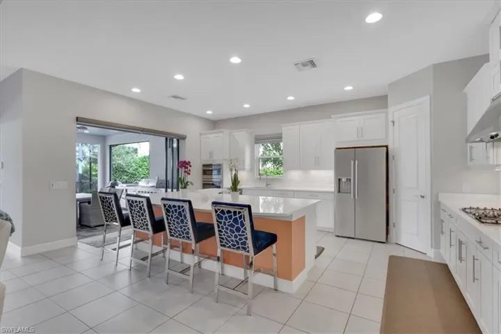Kitchen featuring stainless steel appliances, a center island, white cabinets, a breakfast bar area, and recessed lighting