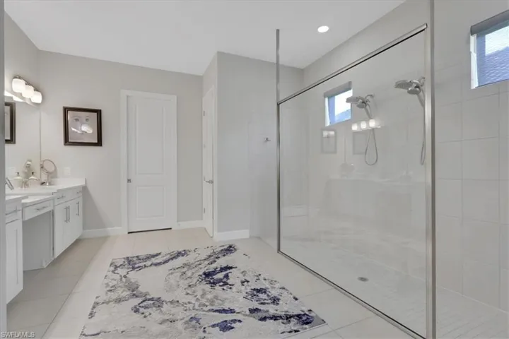 Bathroom featuring vanity, tiled shower, and light tile patterned floors