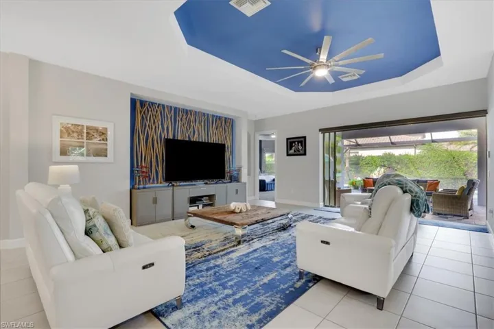 Living room featuring a tray ceiling, a ceiling fan, and tile patterned floors