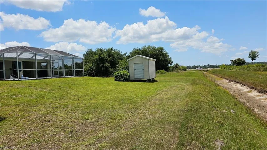View of yard featuring glass enclosure and a shed