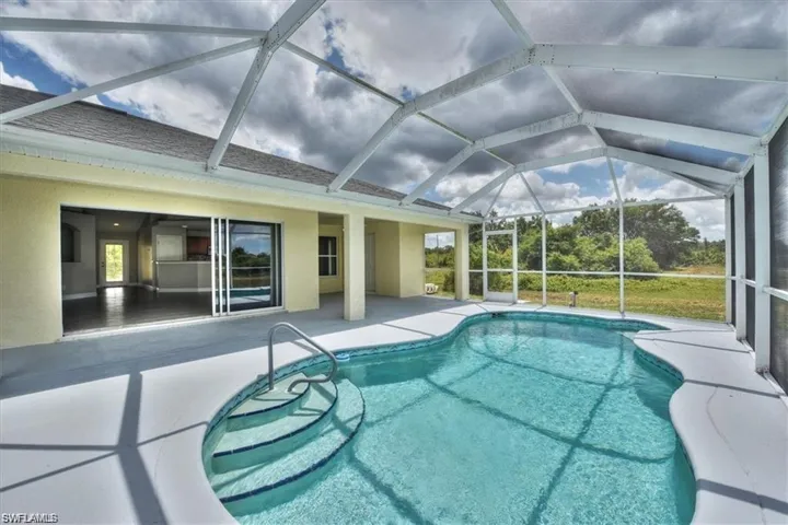 View of pool featuring glass enclosure and a patio area