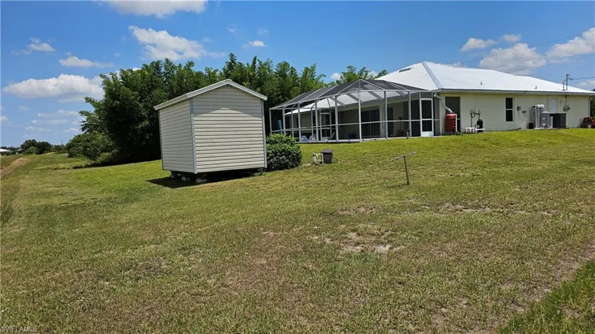 Back of house featuring a lawn and a lanai