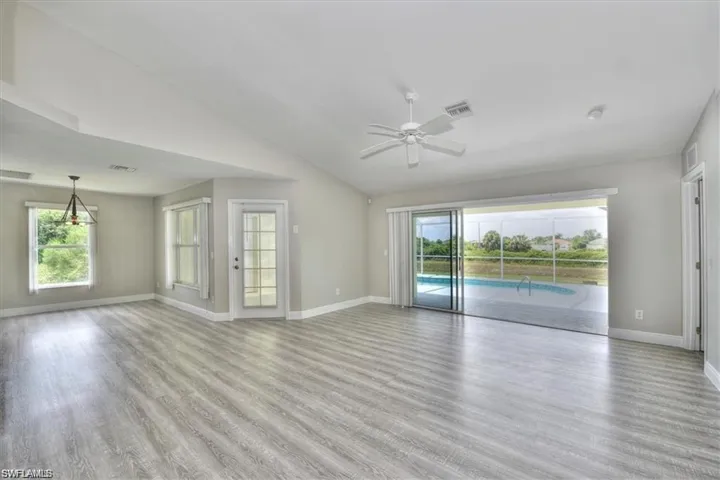 Empty room featuring ceiling fan, vaulted ceiling, and light wood-type flooring