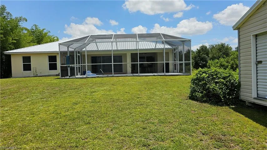 Back of house featuring a lawn and a lanai