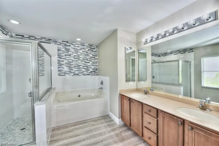Bathroom with hardwood / wood-style flooring, vanity, and separate shower and tub