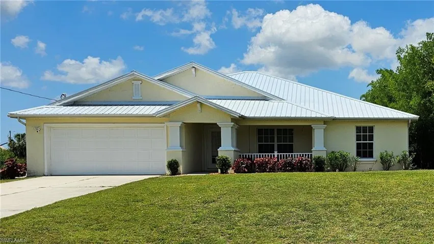 View of front of property with covered porch, a garage, and a front yard