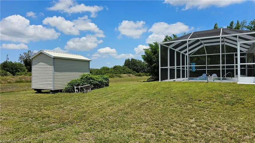 View of yard featuring a lanai, a shed, and a pool