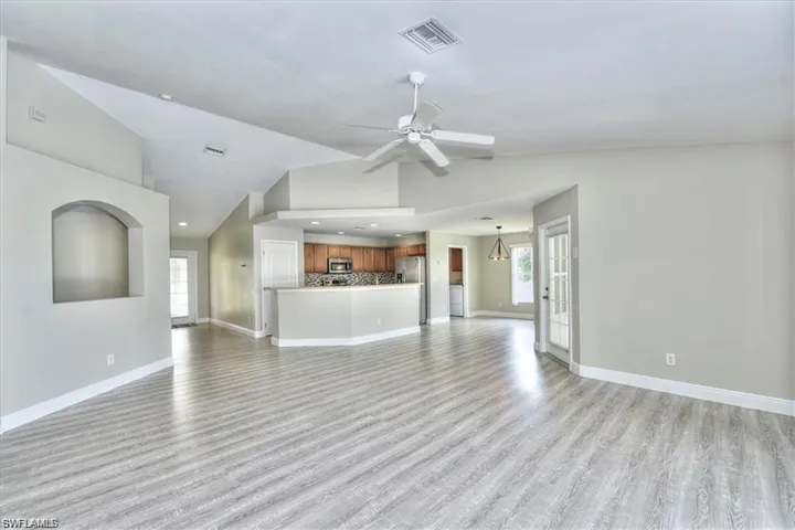Unfurnished living room featuring light hardwood / wood-style flooring, ceiling fan, and lofted ceiling