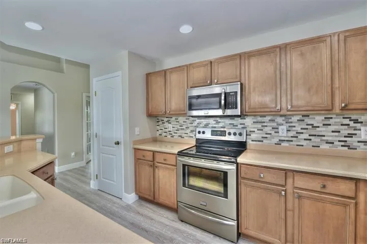 Kitchen with backsplash, sink, stainless steel appliances, and light hardwood / wood-style floors