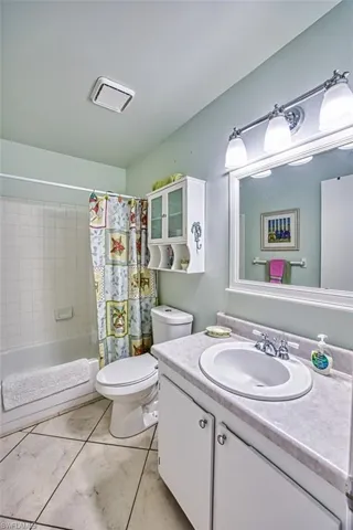 Bathroom with vanity, shower / bathtub combination with curtain, and light tile patterned floors