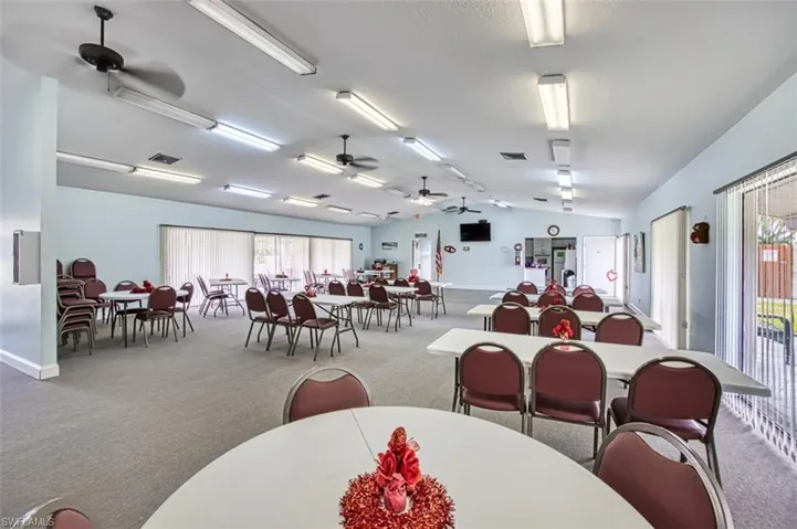 Dining area featuring light colored carpet, vaulted ceiling, plenty of natural light, and ceiling fan