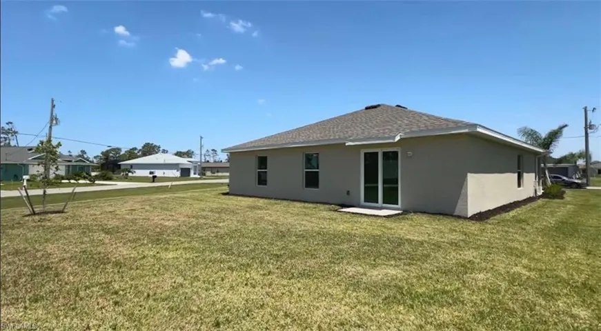 Back of house featuring stucco siding, a lawn, and roof with shingles