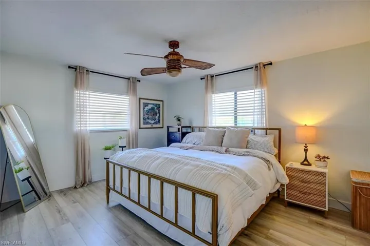 Bedroom with ceiling fan, light wood-type flooring, and multiple windows
