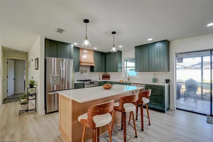 Kitchen with a breakfast bar, sink, stainless steel appliances, and custom range hood