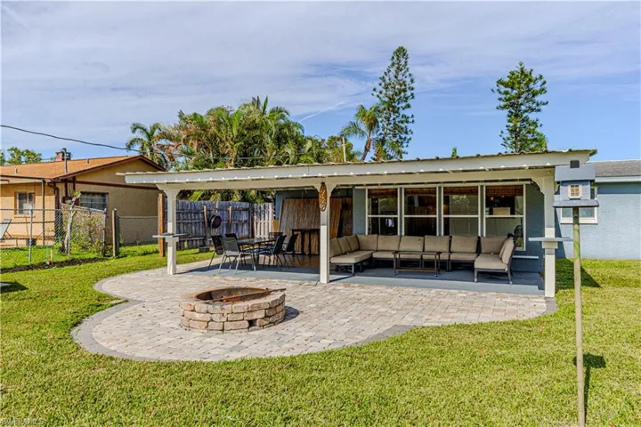 Back of property with a lawn, a patio area, and an outdoor living space with a fire pit