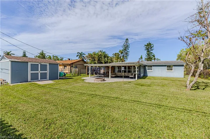 Rear view of property with a yard, an outdoor fire pit, and a patio area