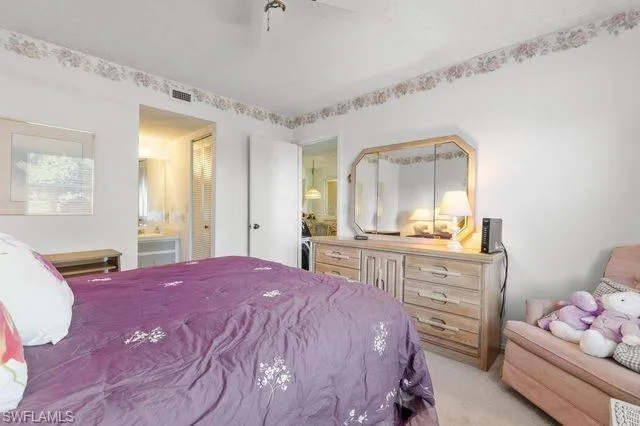 Bedroom with light colored carpet, ensuite bathroom, and ceiling fan