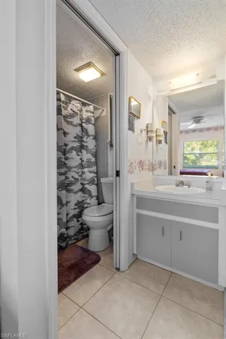 Bathroom featuring tile flooring, vanity, toilet, and a textured ceiling