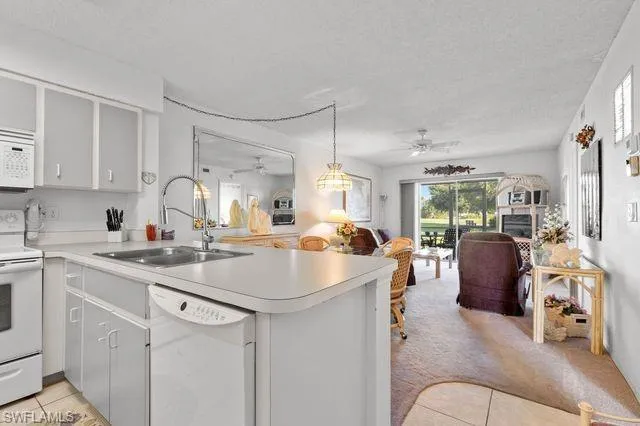 Kitchen featuring ceiling fan, sink, white appliances, and kitchen peninsula
