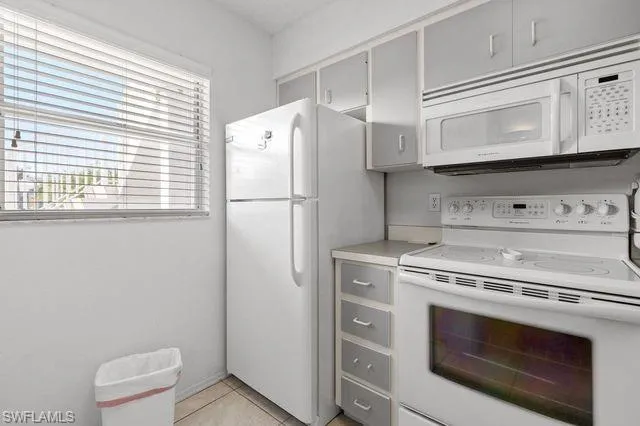 Kitchen with white appliances, gray cabinetry, and light tile floors